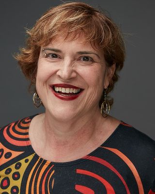 Anne F Pugh Photo of woman wearing stiped scoop neck shirt, with short hair, smiling, with red lipstick